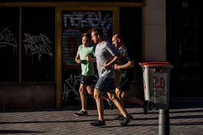 Tres hombres corren juntos por la acera en La Latina, el miércoles.
