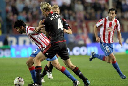 El Kun intenta zafarse de la defensa del Bayer.