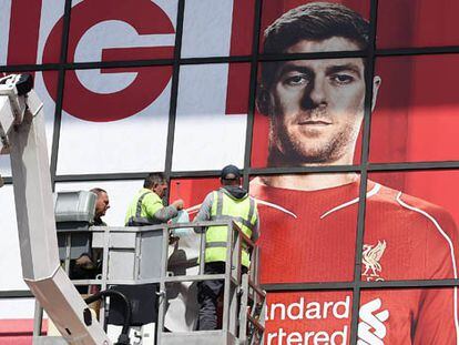 Operarios colocan un mural con el rostro de Gerrard en Anfield