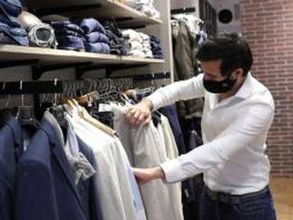 Un hombre protegido con una mascarilla realiza unas compras en una tienda en Madrid.