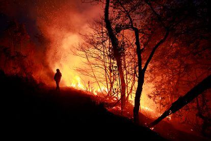 Un bombero intenta sofocar el incendio en Piedrafita (Asturias), el viernes.