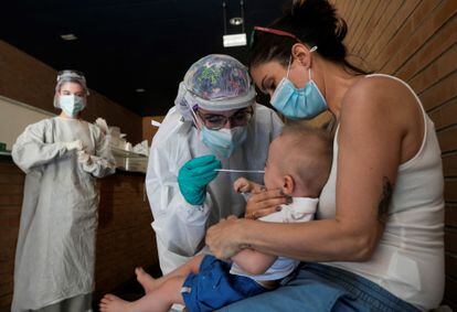 Una sanitaria realiza una PCR a un niño en un espacio habilitado fuera de un centro de salud de Zaragoza, en julio.