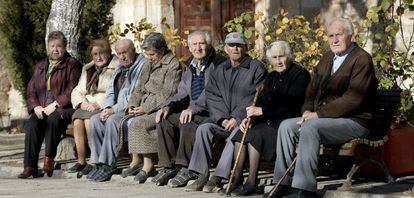 Varios ancianos toman el sol en unos bancos de Olmeda de la Cuesta, Cuenca. 