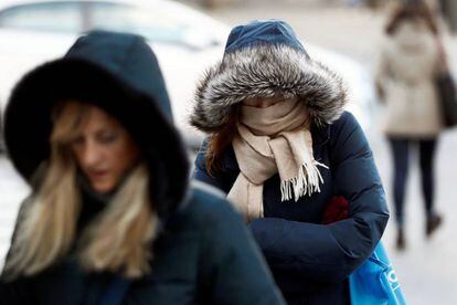 Una mujer se protege del frío a primera hora la mañana en una céntrica calle de la capital.