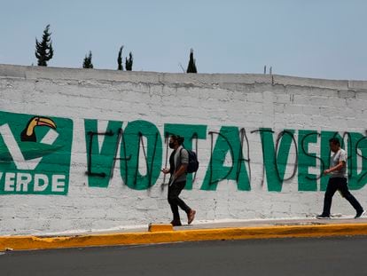 Peatones frente a una barda pintada con el logo del Partido Verde, antes de las elecciones de junio 2021, en Ciudad de México.