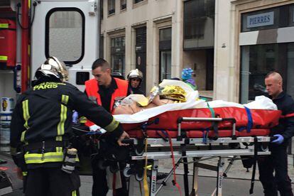 Los bomberos llevan a un hombre herido en una camilla frente a las oficinas del Diario satírico francés Charlie Hebdo en París.
