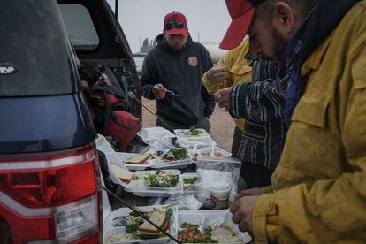 Varios bomberos recogen su desayuno en el campamento de Paisley, después de 14 horas de trabajo.