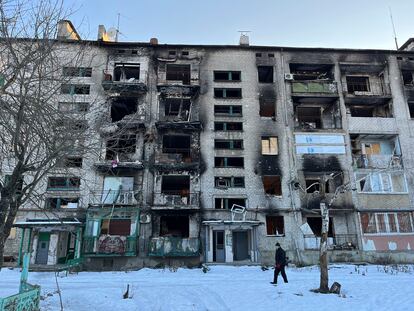 Un vecino de Limán, en la provincia de Donetsk, camina sobre la nieve ante un edificio bombardeado.