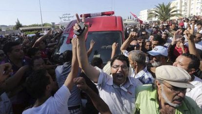 Varios tunecinos protestan junto a la ambulancia que carga el cuerpo del opositor pol&iacute;tico Mohamed Brahmi.