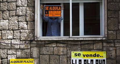 Un hombre coloca un cartel de alquiler en una vivienda de Madrid.