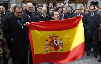 Un home desplega una bandera espanyola davant la presència de Francesc Homs i de l'expresident de la Generalitat Artur Mas, entre d'altres, durant el recorregut a peu que han fet cap a la seu del Tribunal Suprem de Madrid.