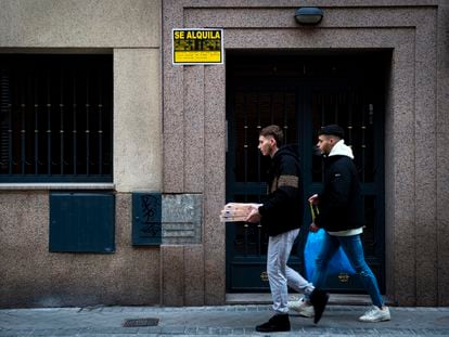 Dos jóvenes pasan frente a un piso con una vivienda en alquiler en Madrid.