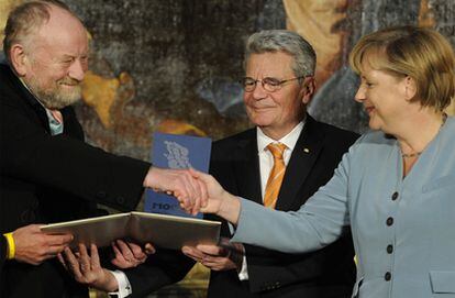 Kurt Westergaard recibe de manos de Angela Merkel, en Postdam, el premio M100 a la libertad de prensa, en presencia de Joachim Gauck, en tutor de los archivos de la Stasi, en el centro.