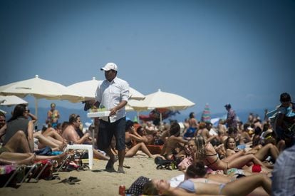 Un venedor ambulant ofereix mojitos a la platja de la Barceloneta.