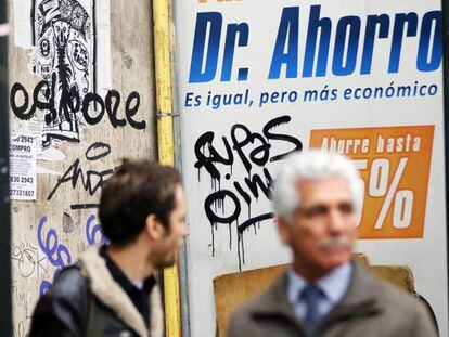 Dos personas caminan frente a un anuncio en Santiago de Chile el pasado martes.