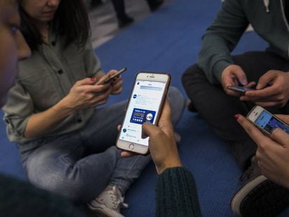 Varios jóvenes usan sus teléfonos móviles.