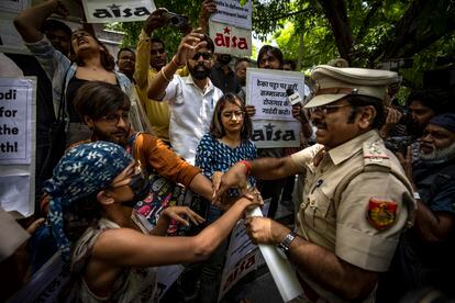 Un oficial de policía arrebata este viernes las pancartas a los estudiantes durante una manifestación en Nueva Delhi, la India.