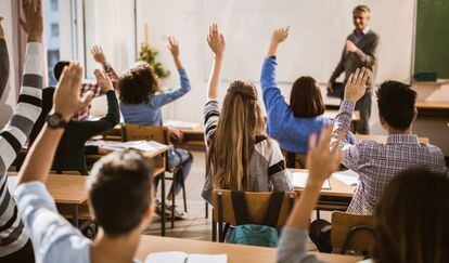 Unos alumnos levantan la mano para contestar a una pregunta.