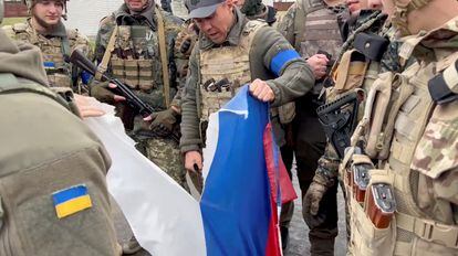 El alcalde del distrito de Derhachi, Vyacheslav Zadorenko, con un grupo de soldados, rasga una bandera rusa en Kozacha Lopan, en la región de Járkov (Ucrania), este lunes.