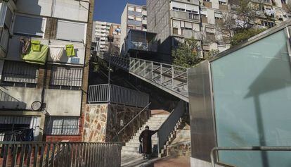 Una vecina sube por una escalera en la calle Calle Rasos de Peguera, en el barrio Ciutat Meridiana, en Barcelona.