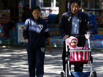 Un abuelo pasea con su nieto y su hija por un parque de Pek&iacute;n (China).