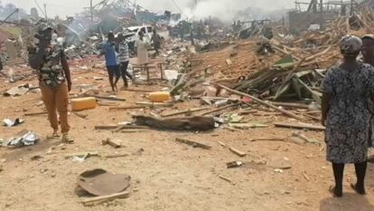 Un grupo de personas camina junto a los restos dejados tras la explosión de un camión en Ghana.