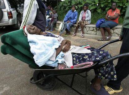 Un hombre traslada a una mujer afectada por el cólera a un hospital de Harare.