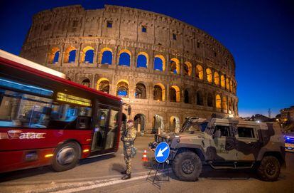 Un autobús pasa al lado de un soldado italiano patrullando la zona del antiguo Coliseo de Roma (Italia) como medida de seguridad en las zonas donde se espera una multitud de personas.