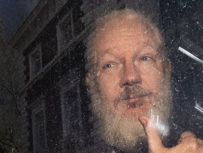 Assange saluda desde el interior del coche de policía que lo traslada, este jueves en Londres.