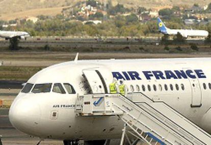 El Airbus A321 de Airfrance en el aeropuerto de Barajas este jueves, y personal sanitario con trajes de protecci&oacute;n.