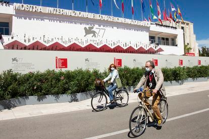 Asistentes al festival pasean en bicicleta frente al palacio del festival, este martes en Venecia.