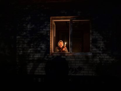 Una mujer sostiene una vela en la ventana de su casa durante un corte de energía en Borodyanka (Ucrania), en octubre pasado.