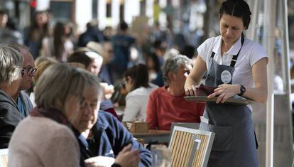 Una camarera atiende a unos clientes en una terraza en Valencia.