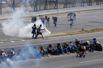 Partidarios de la oposición devuelven una bomba de gas lacrimógeno lanzada por las fuerzas de seguridad, durante las marchas contra Nicolás Maduro.