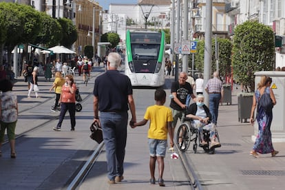 The tram being tested passes through Calle Real de San Fernando, Cádiz, sharing the avenue with authorized pedestrian and car traffic, still in its testing phase in white