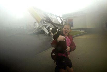 Cinthia Gonzales corre a través de la fuerte lluvia llevando a un perro que ha rescatado de una gasolinera en Gretna, Luisiana, el 29 de agosto de 2005.