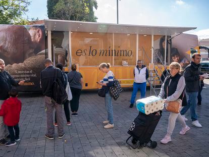 Un grupo de personas hace cola para entrar en un autobús que informa sobre el Ingreso Mínimo Vital, en Parla (Madrid) el pasado octubre.