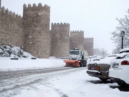 Una máquina quitanieves trabaja para retirar la nieve caída junto a la muralla de Ávila.