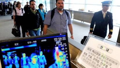Unos viajeros pasan por un control de temperatura corporal en el aeropuerto de Seúl (Corea del Sur).