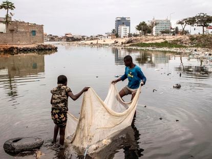 Dos niños usan una red para pescar en un lago cerca de Luanda (Angola), en agosto de 2022.