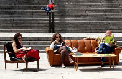 Varias personas leen en un sal&oacute;n de lectura al aire libre en Madrid.