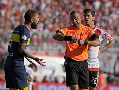El árbitro Diego Abal (centro) conversa con Gino Peruzzi (izquierda) del Boca Juniors.