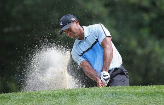 Tiger Woods patea desde el búnker en el noveno hoyo.
