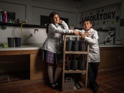 Ana Lucía Gutiérrez y Thomas Arango, estudiantes del colegio Montessori, posan junto a un generador de energía a partir de desechos de café, en Huila (Colombia), el 3 de noviembre de 2023.