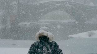 A person walks near the Gapstow Bridge in Central Park during a winter storm on February 1, 2021 in New York City. - A powerful winter storm is set to dump feet of snow along a stretch of the US east coast including New York City on February 1, 2021, after blanketing the nation's capital. The National Weather Service issued storm warnings from Virginia to Maine -- a swathe home to tens of millions of people -- and forecast snowfall of 18 to 24 inches (45-60 centimeters) in southern New York, northeastern New Jersey and parts of southwest Connecticut. (Photo by TIMOTHY A. CLARY / AFP)