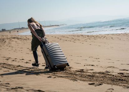 Una turista arrastra su maleta en una playa de Andalucía
