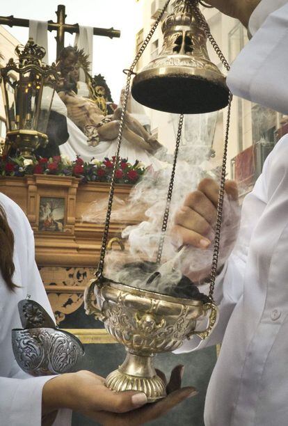 <b>MIÉRCOLES SANTO. Huelva.</b> Dos acólitos encienden el incensario ante el Santo Sudario de Nuestro Señor Jesús de la Providencia de la Cofradia de la Santa Cruz, durante su recorrido por las calles de Huelva.