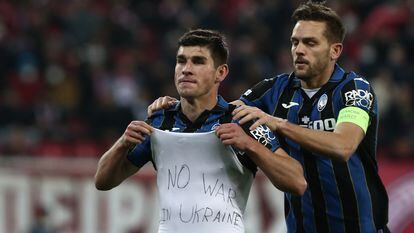 El ucranio Ruslan Malinovskyi (izquierda) muestra un mensaje en contra de la guerra junto a Rafael Tolói durante el Olympiacos - Atalanta de la Liga Europa.