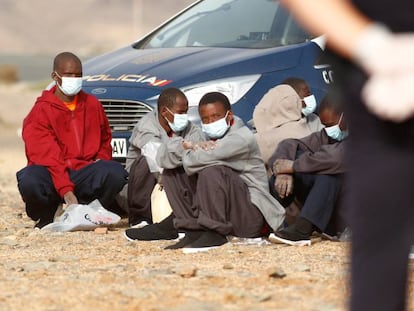 Un grupo de migrantes subsaharianos llegados en patera es vigilado por la policía nacional en la playa Aeroclub de la localidad de San Bartolome De Tirajana, en la isla de Gran Canaria, el 28 de agosto de 2020.