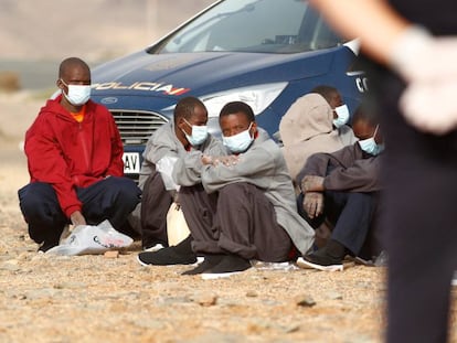 Un grupo de migrantes subsaharianos llegados en patera es vigilado por la policía nacional en la playa Aeroclub de la localidad de San Bartolome De Tirajana, en la isla de Gran Canaria, el 28 de agosto de 2020.  